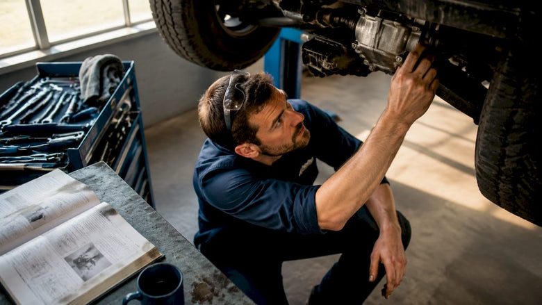 Technician inspecting vehicle drivetrain in garage