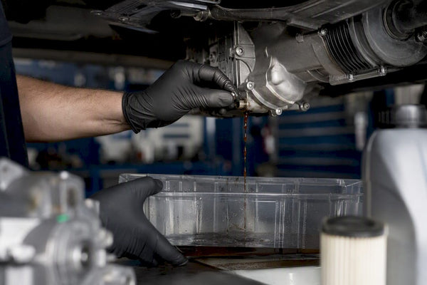 Hands draining old Haldex fluid in workshop